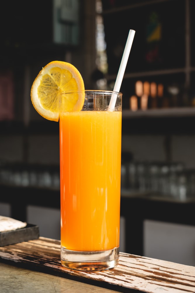 zumo de naranja en vaso de tubo en barra de bar